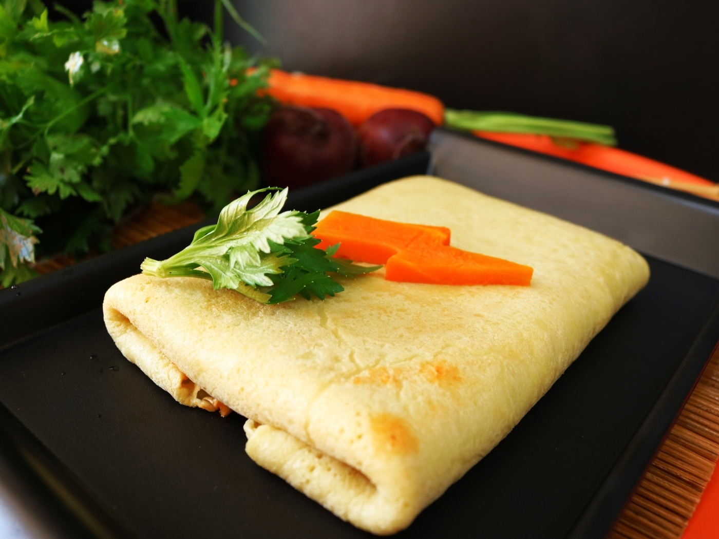 Блинчик на тарелке с морковью и веточками петрушки