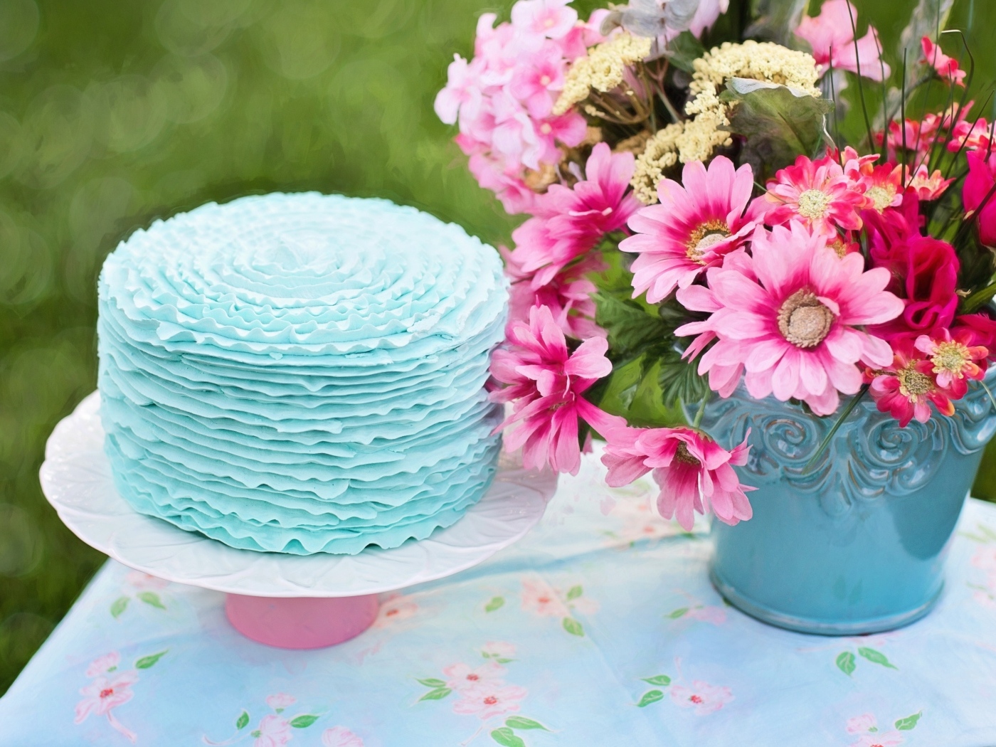 Торт с голубым кремом на столе с цветами