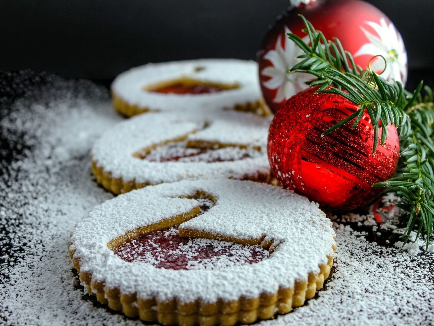 Вкусное сладкое печенье в сахарной пудре на столе с елочными игрушками