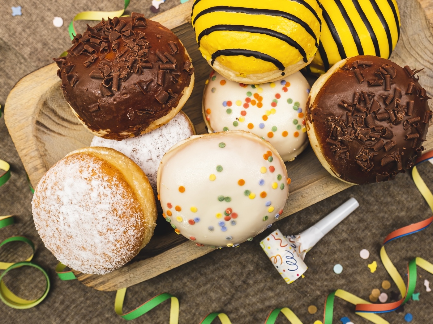 Много сладких пончиков в глазури на столе