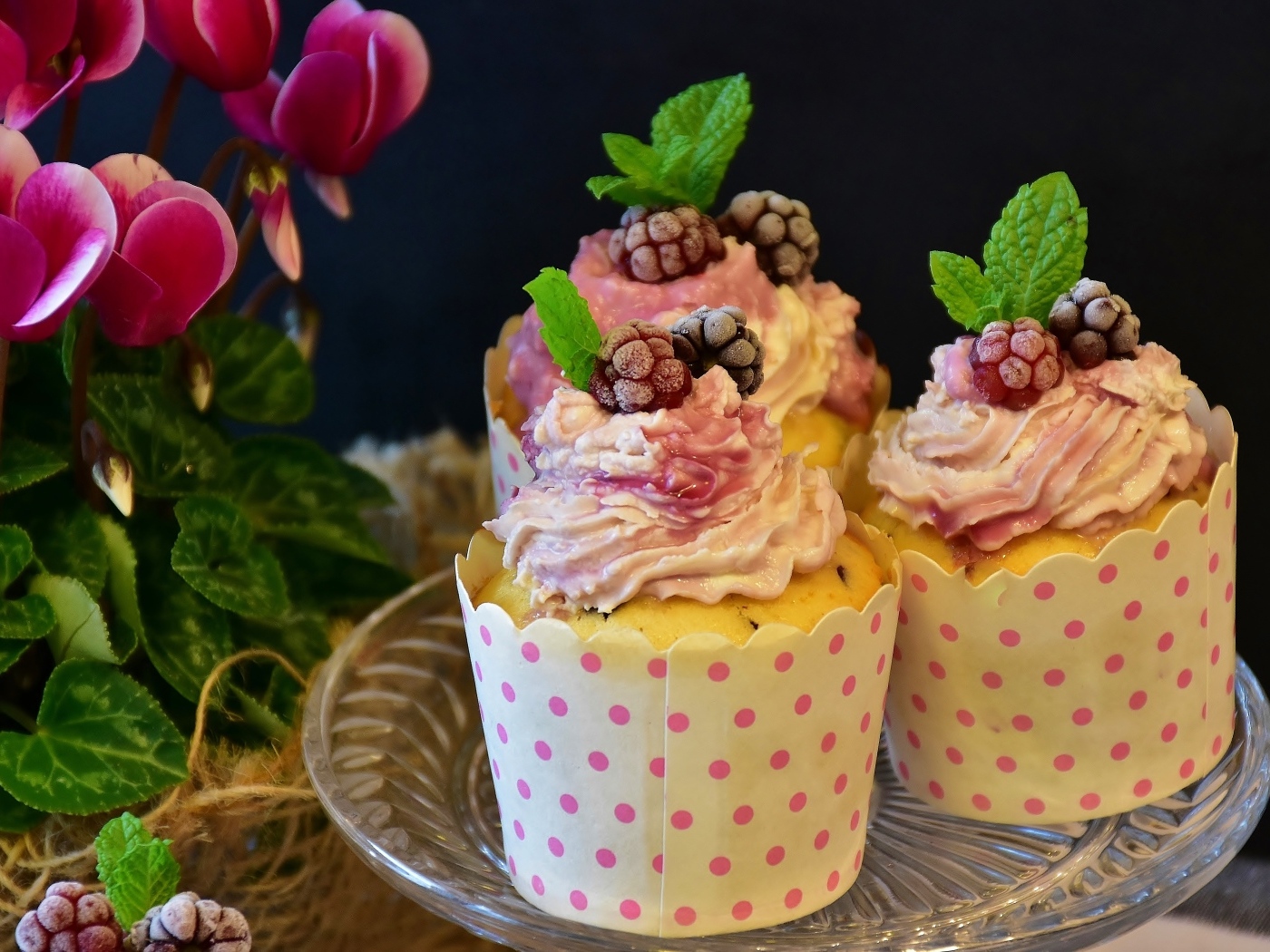 Маффины с кремом и ягодами малины на столе с цветами