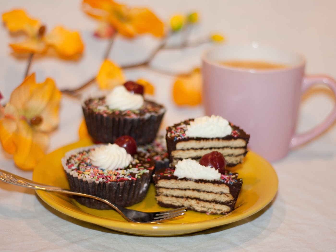 Сладкие вкусные пирожные на столе с чашкой чая и цветами