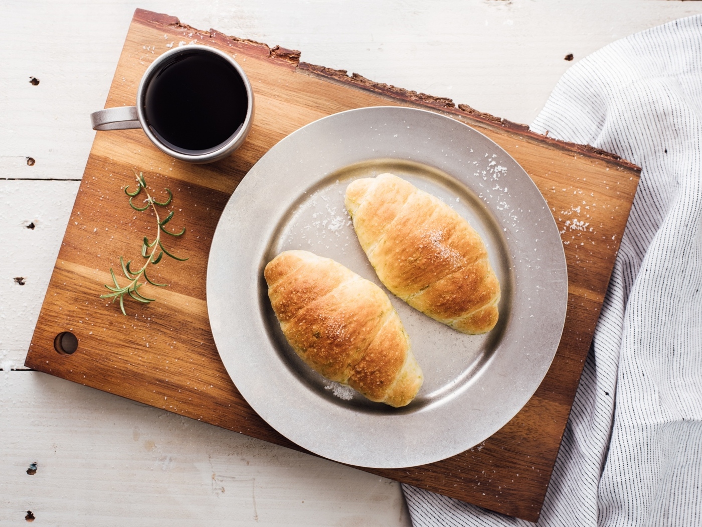 Два круассана на тарелке с чашкой кофе