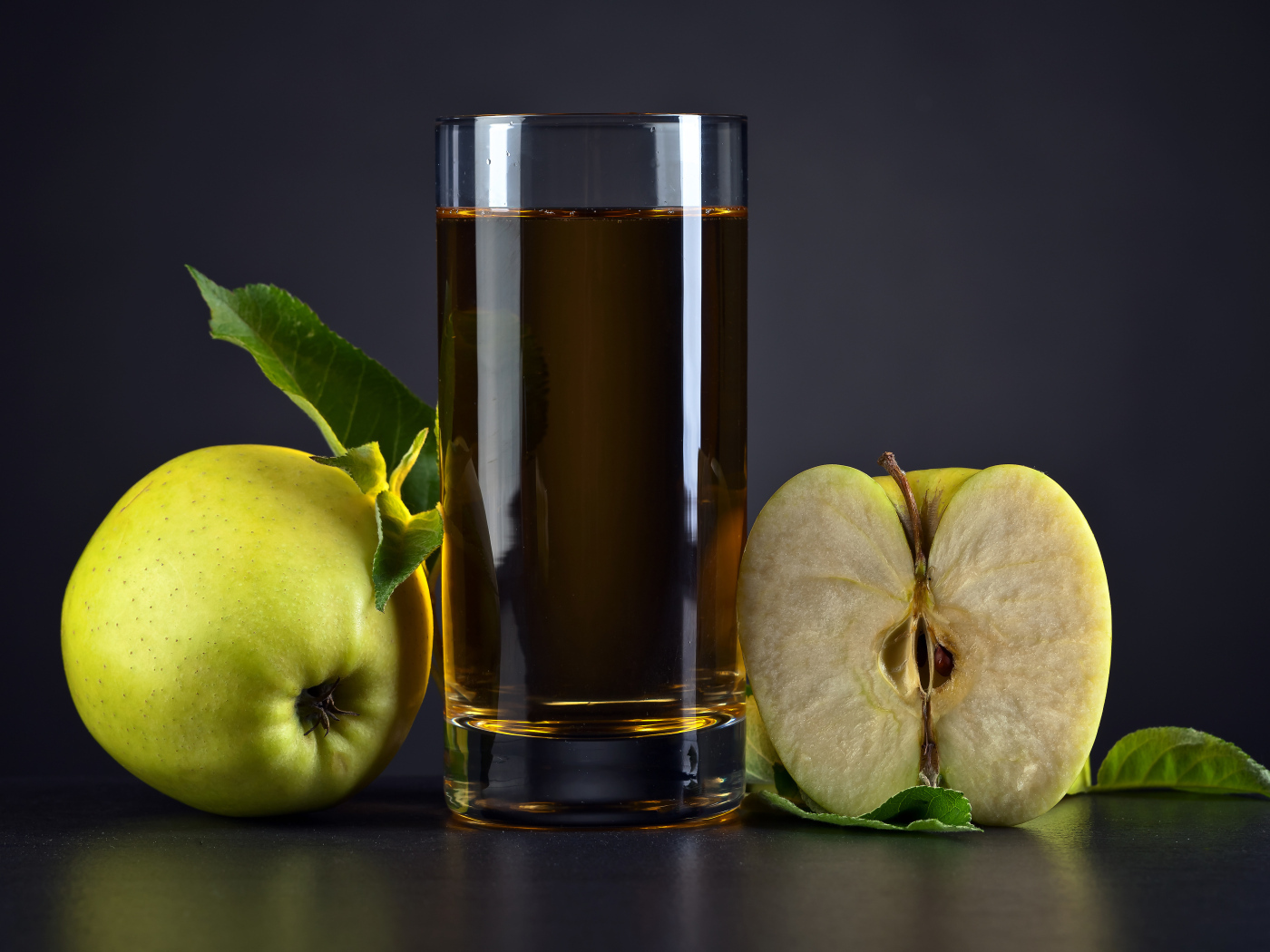 Стакан сока с зелеными яблоками на сером столе