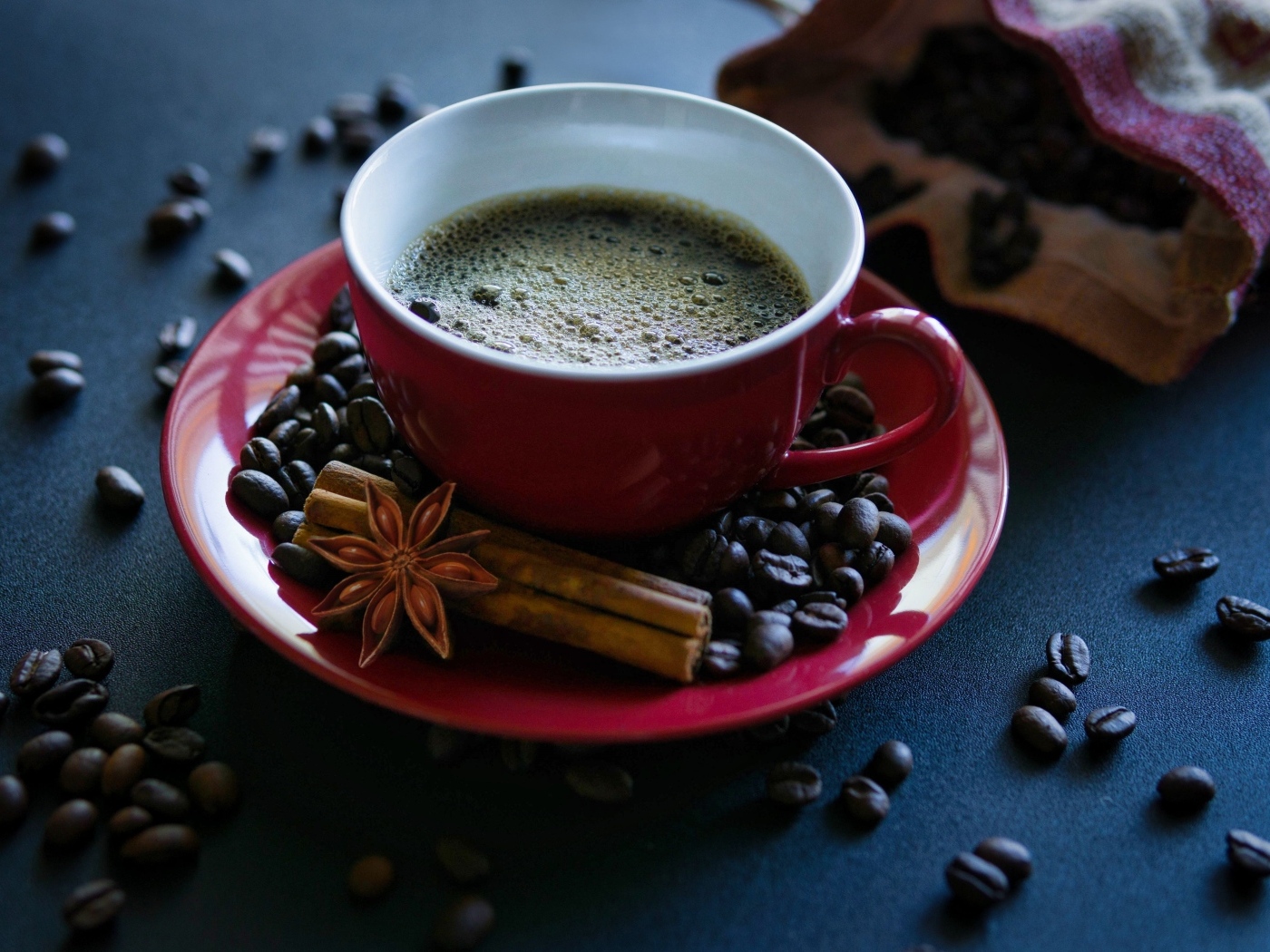 Красная чашка кофе на столе со специями и зернами