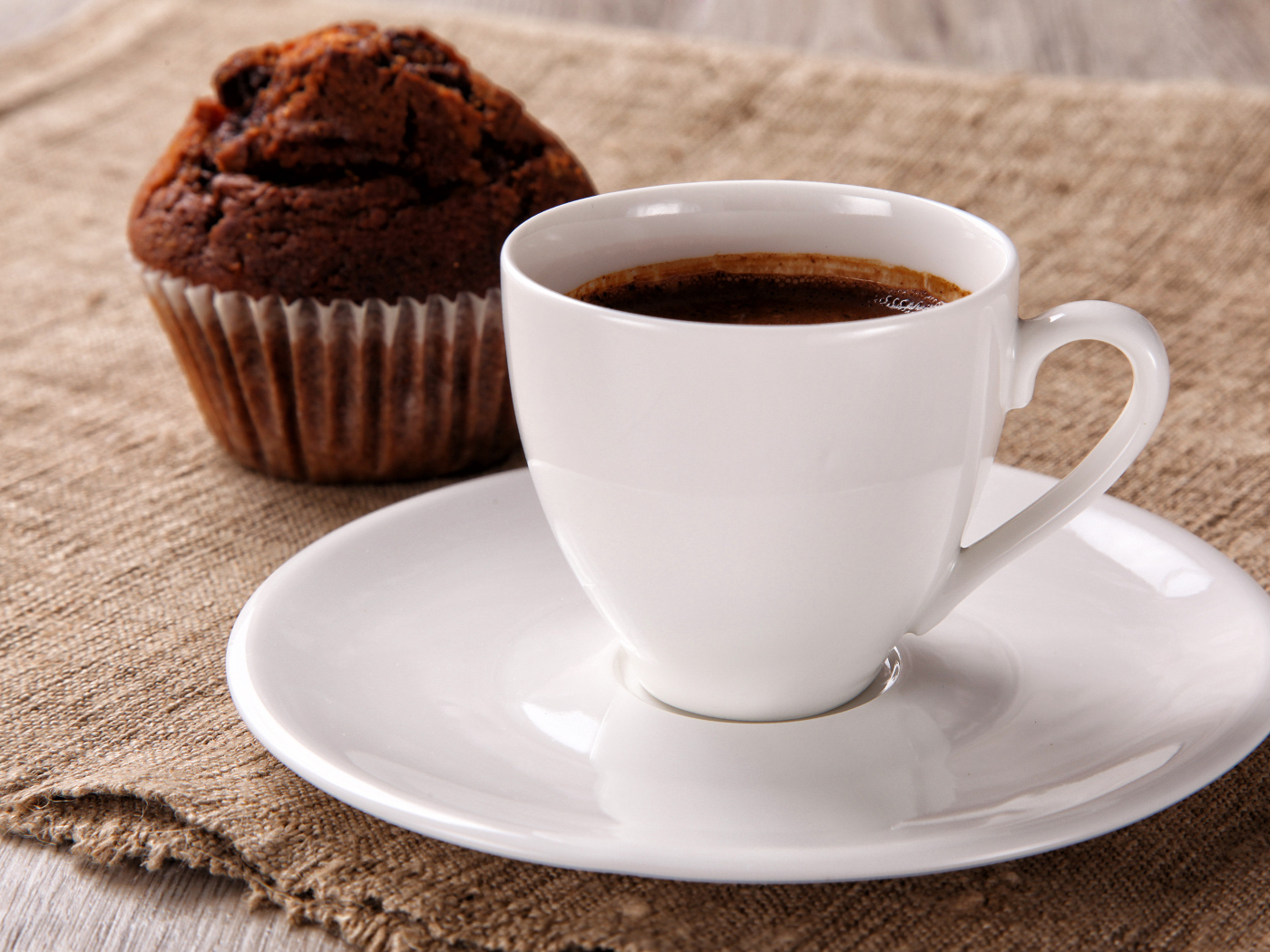 Белая чашка кофе на столе с кексом