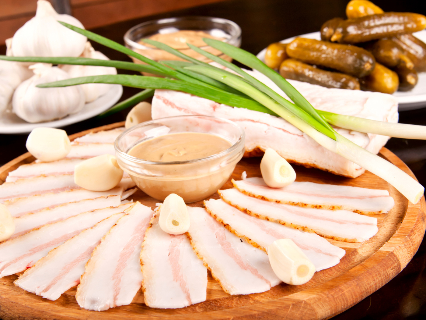 Нарезанное сало с чесноком и солеными огурцами на столе