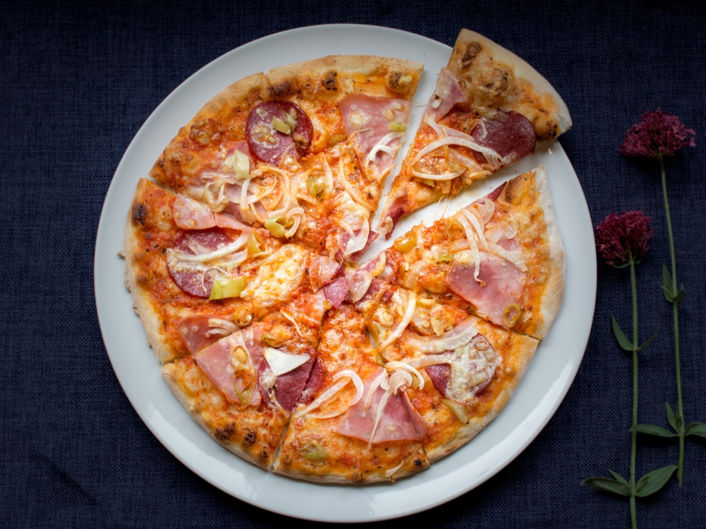 Нарезанная пицца на белой тарелке