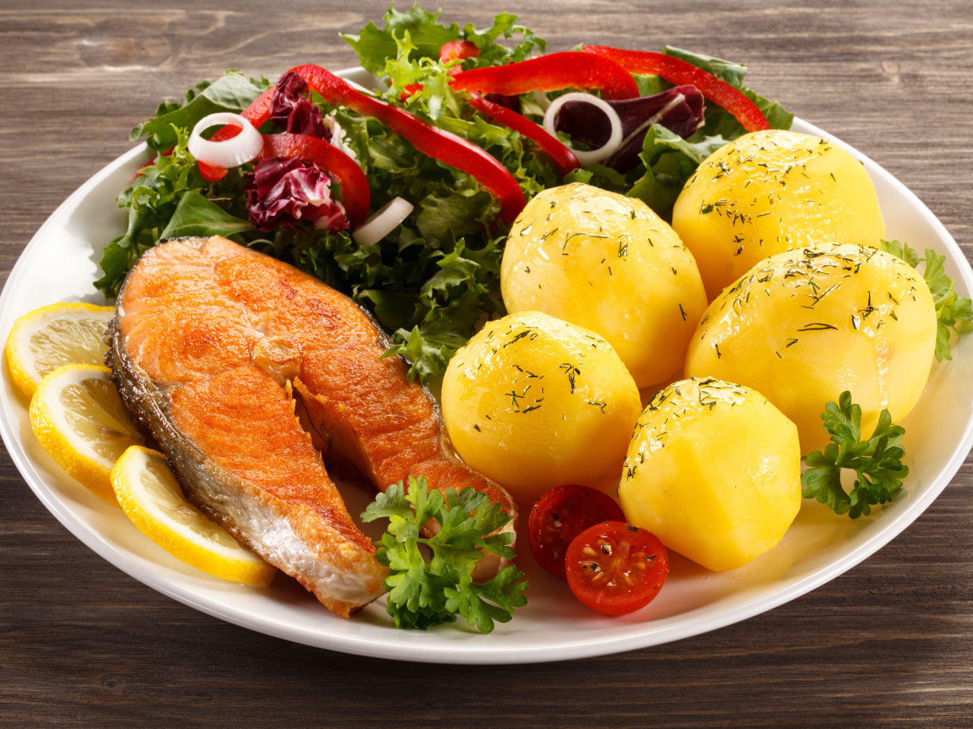 Картофель с кусочками рыбы и зеленью на тарелке