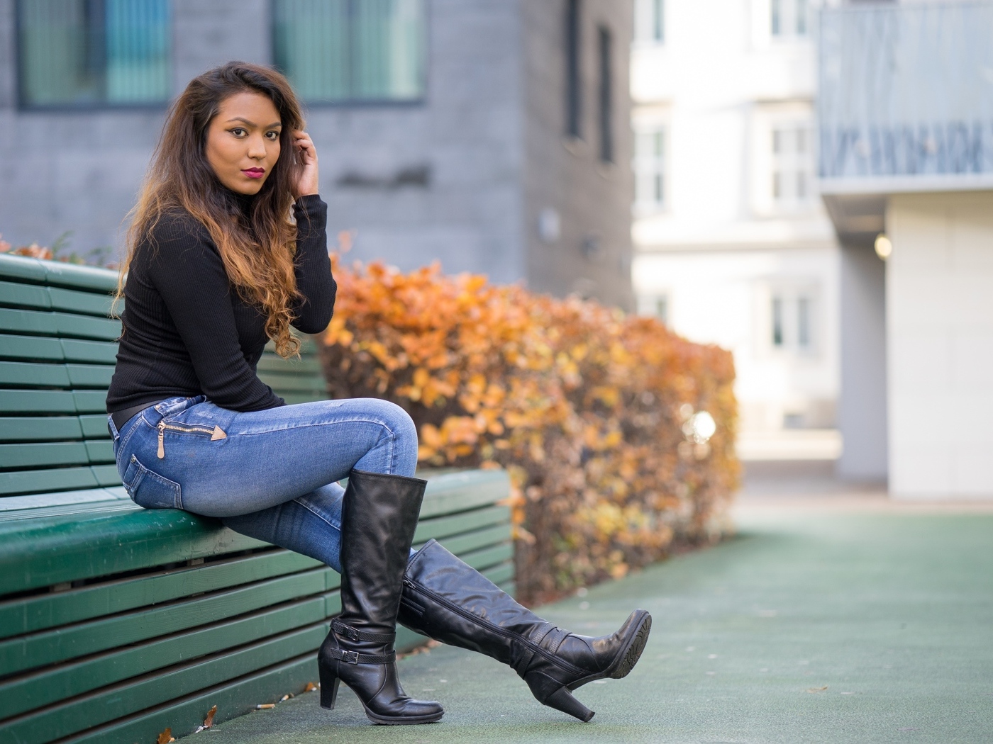 Брюнетка в синих джинсах сидит на лавке