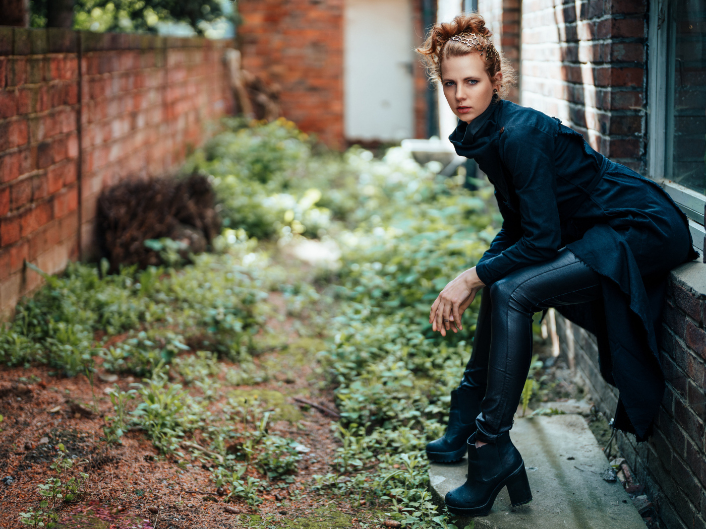 Девушка в черном наряде сидит на окне