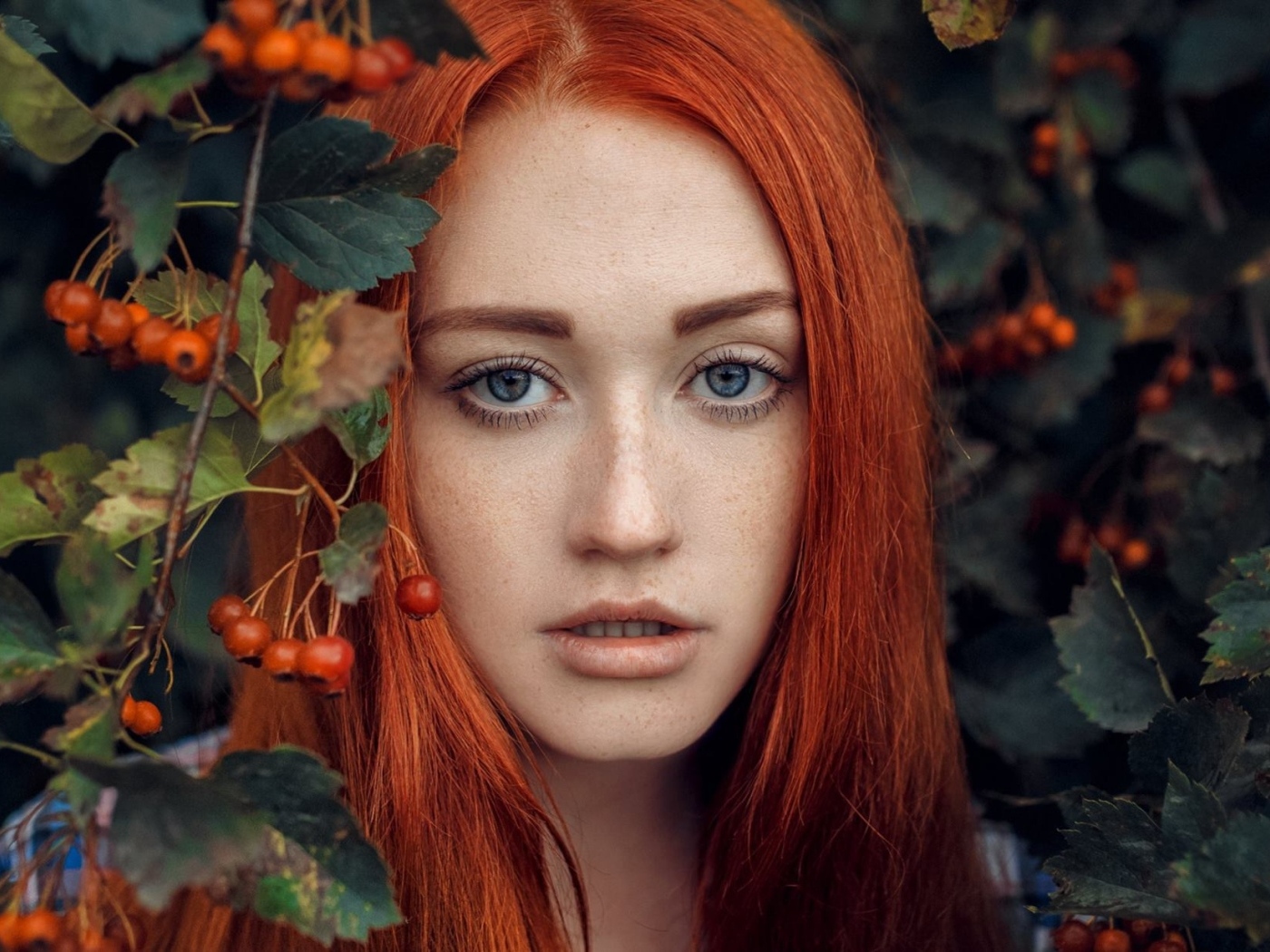 Рыжеволосая девушка стоит у куста с боярышником