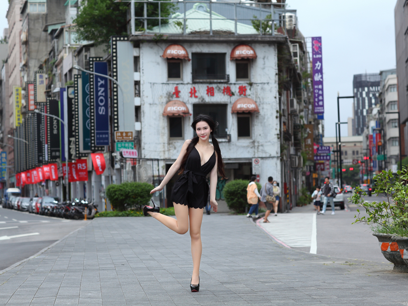 Девушка азиатка в черном платье стоит у дома