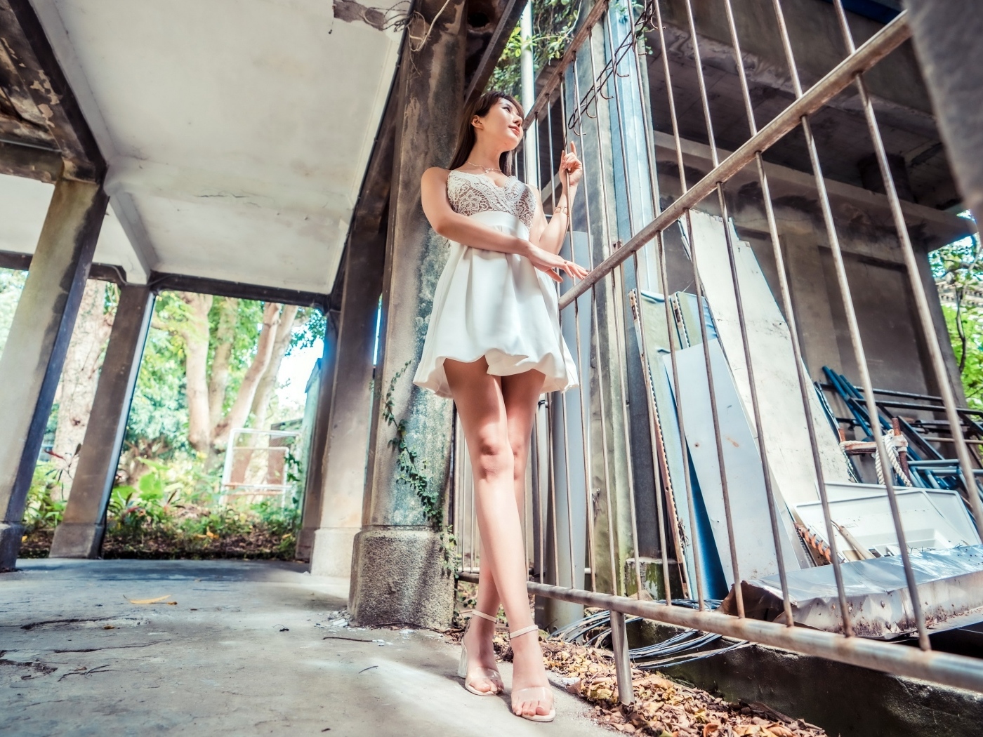 Девушка азиатка в платье стоит у решетки 