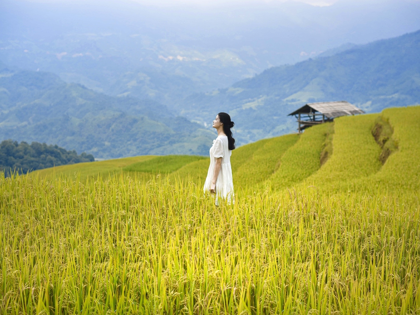 Девушка азиатка в белом платье дышит горным воздухом