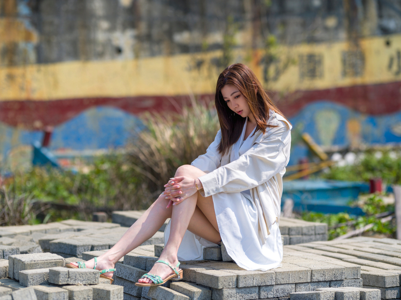 Девушка азиатка в белой рубашке сидит у воды