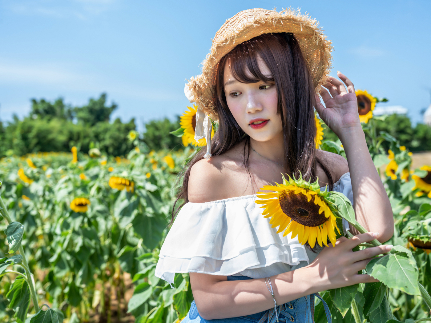 Девушка азиатка на поле с подсолнухами