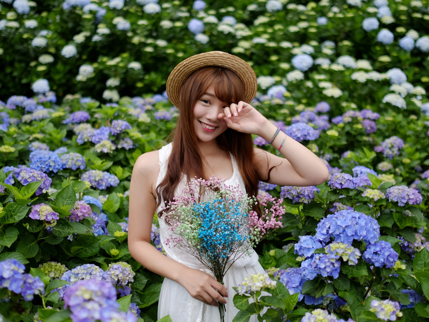 Девушка азиатка у куста с цветами гортензии