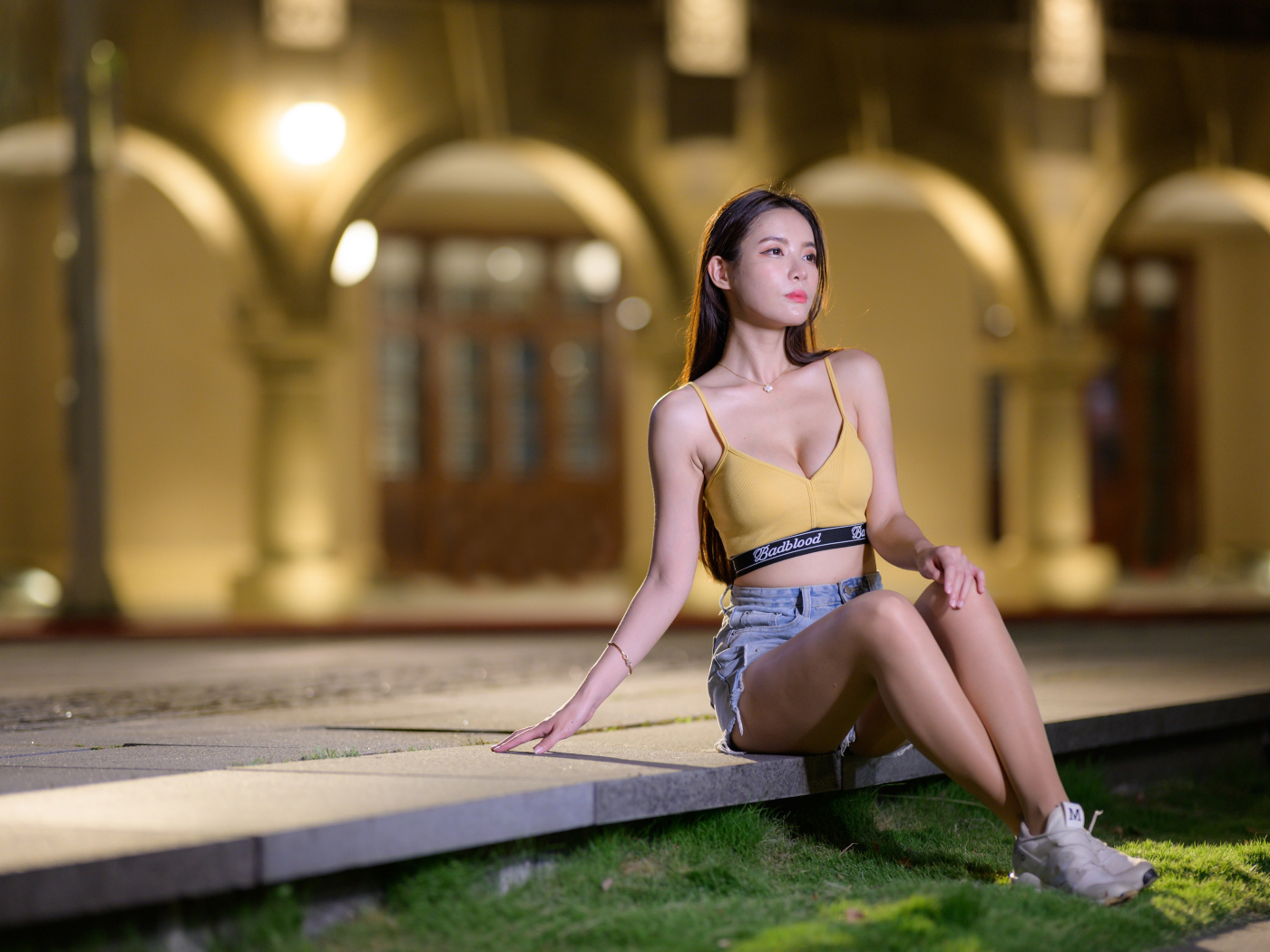 Девушка азиатка сидит на бетонной плите у дома