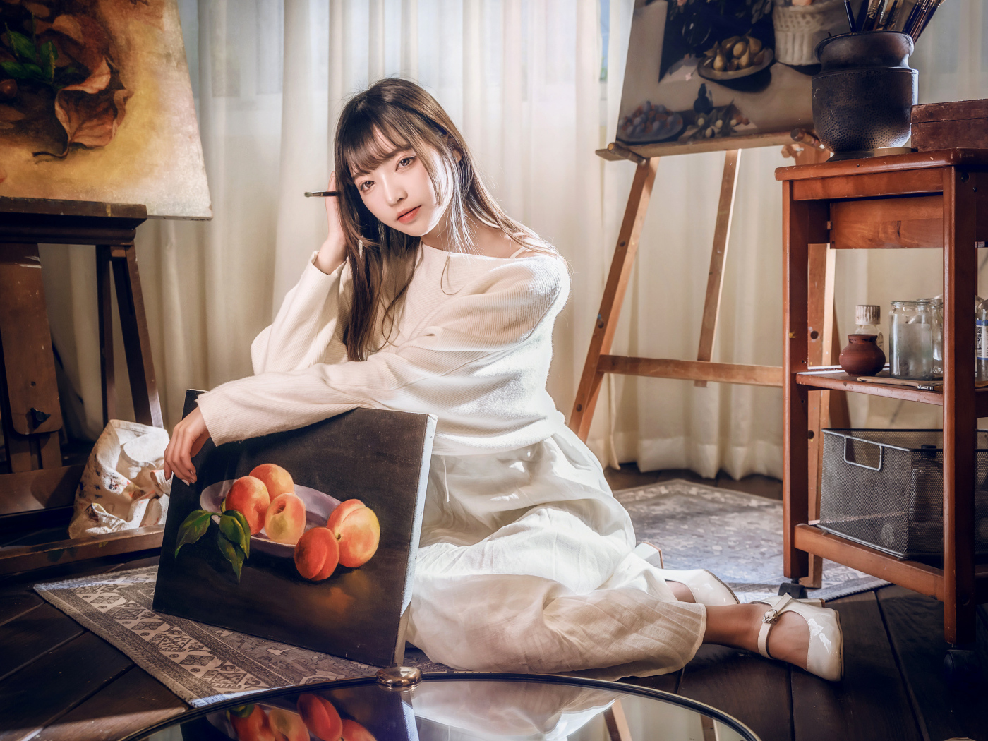 Девушка азиатка сидит с картиной на полу