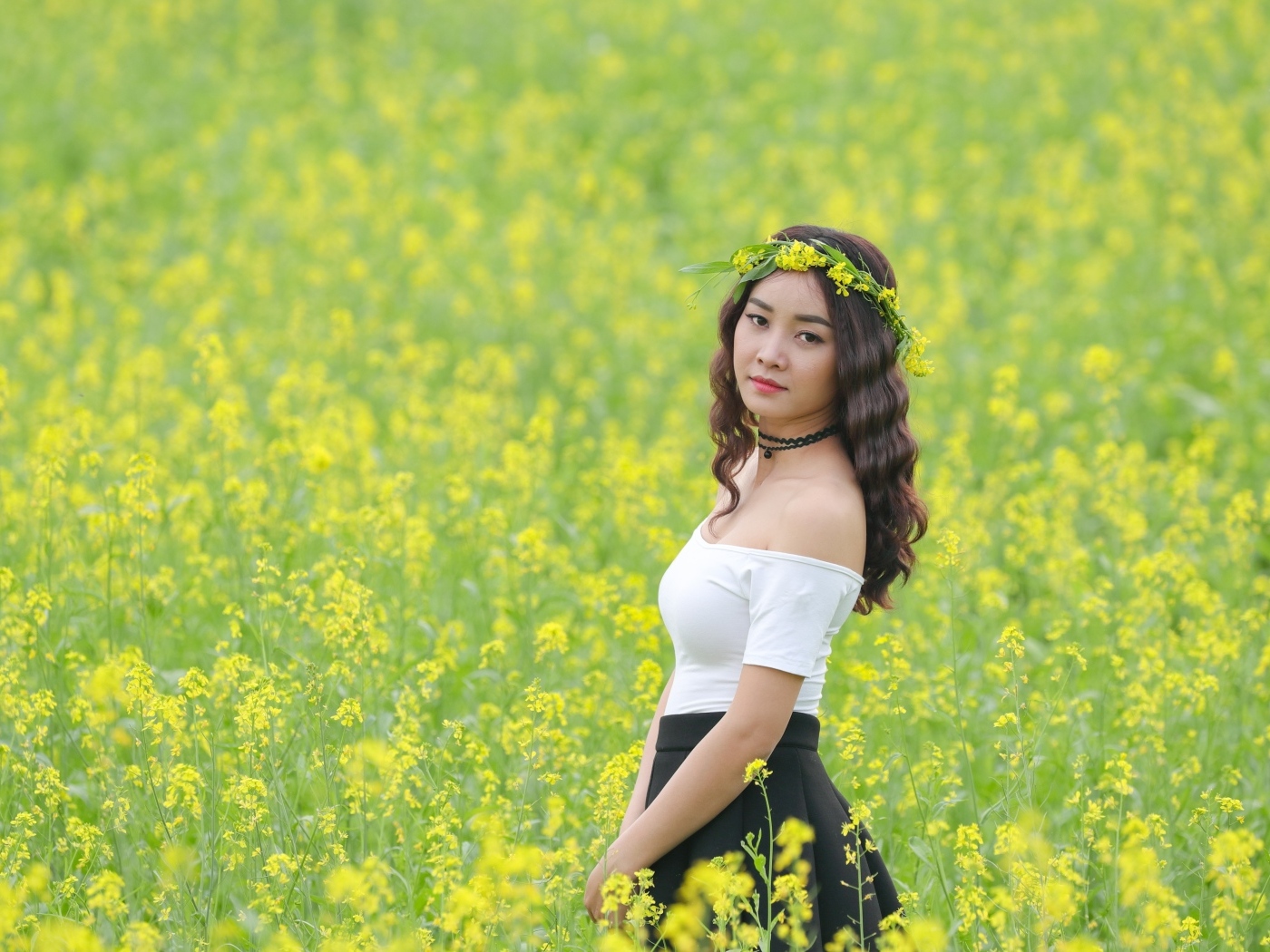 Девушка азиатка стоит на рапсовом поле