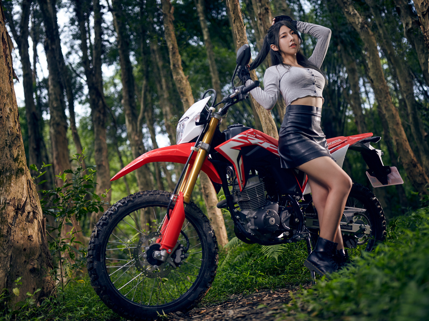 Девушка азиатка с мотоциклом в лесу