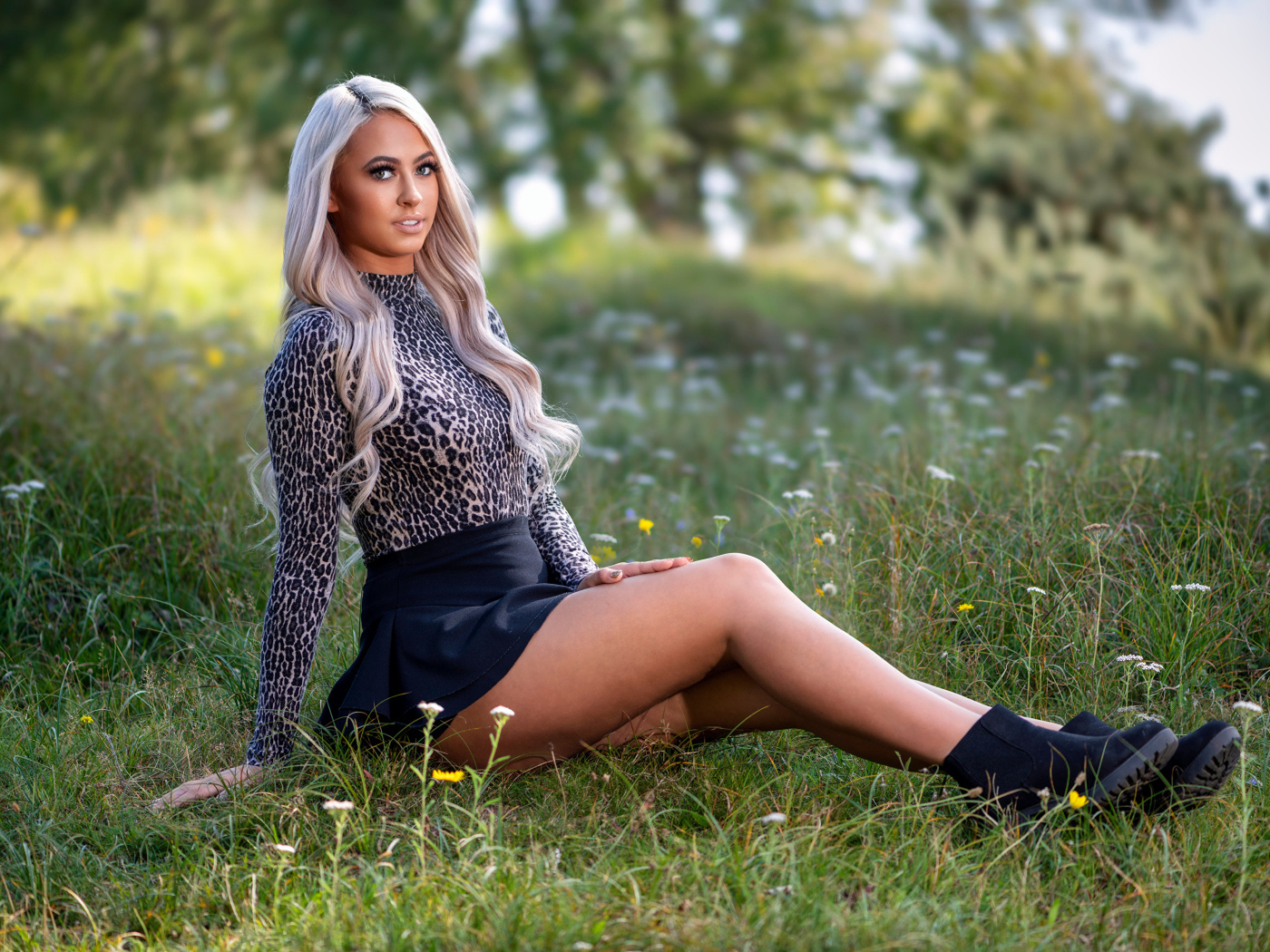 Красивая блондинка в юбке сидит на траве