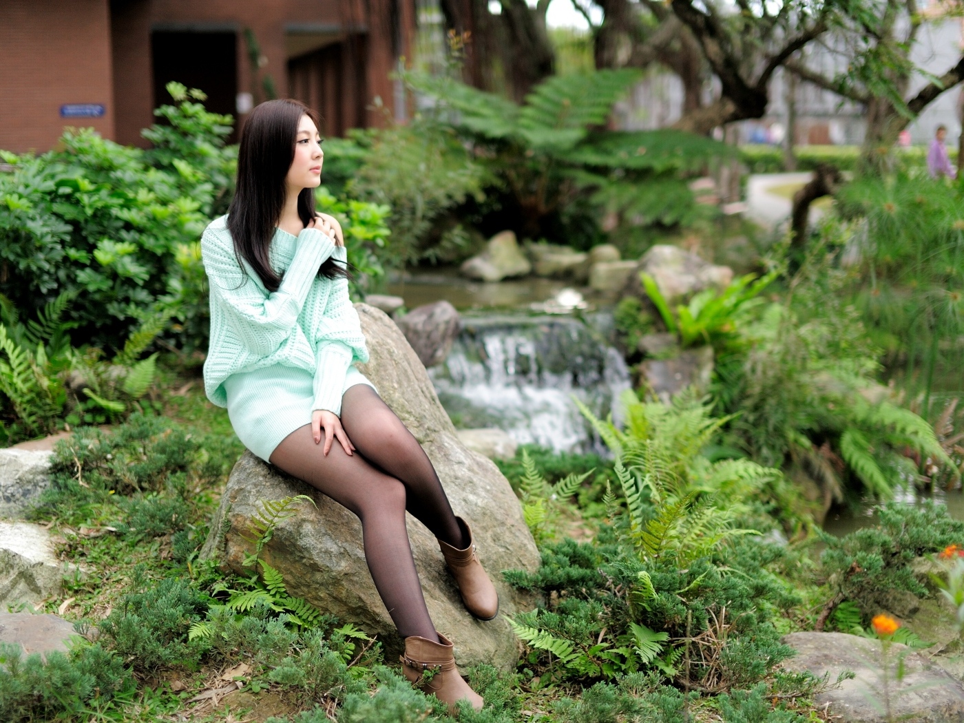 Красивая девушка сидит на камне в парке