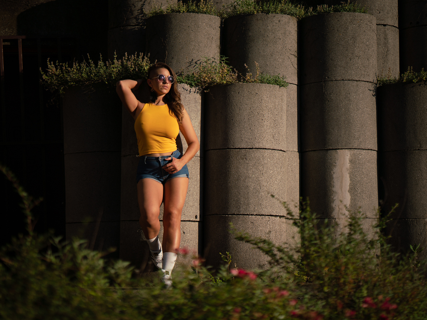 Красивая девушка в очках стоит у стены