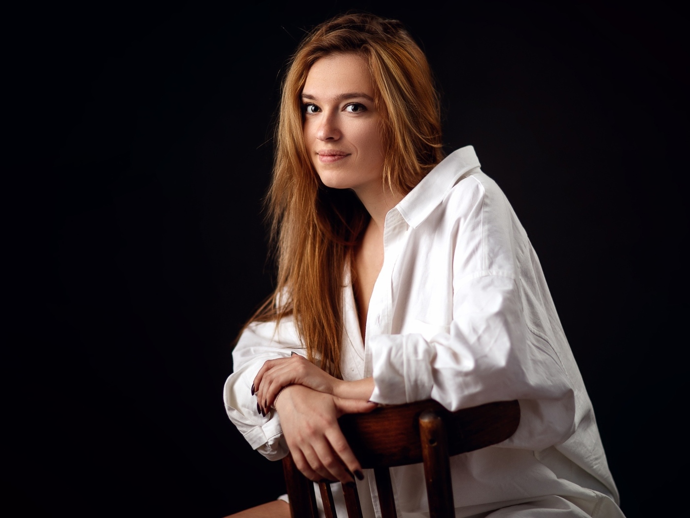 Милая девушка в белой рубашке сидит на стуле