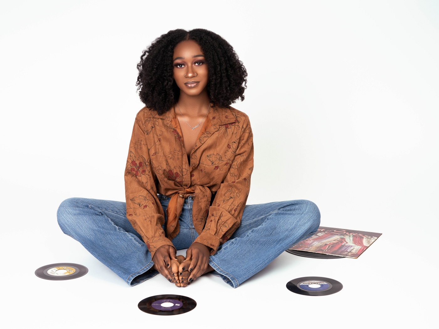 Темнокожая девушка сидит на белом фоне с пластинками