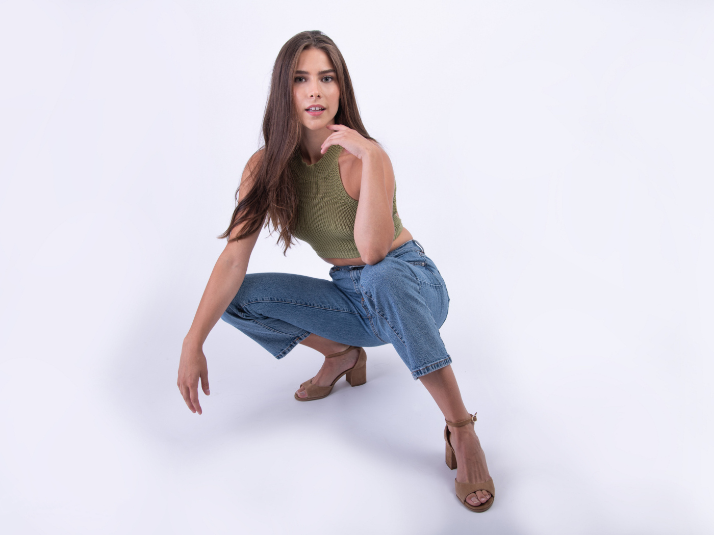 Девушка сидит на корточках на белом фоне