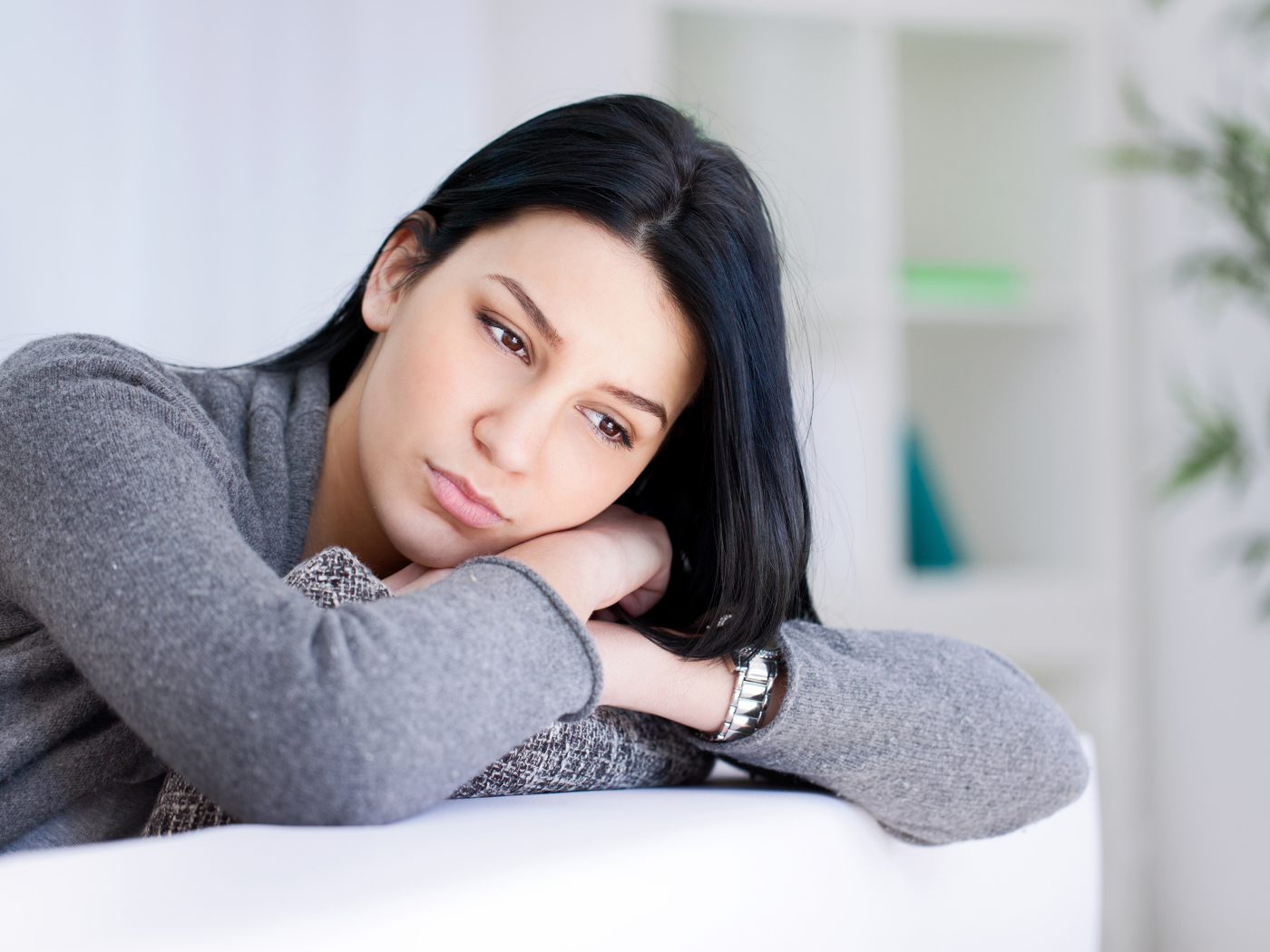 Грустная девушка брюнетка в серой кофте 