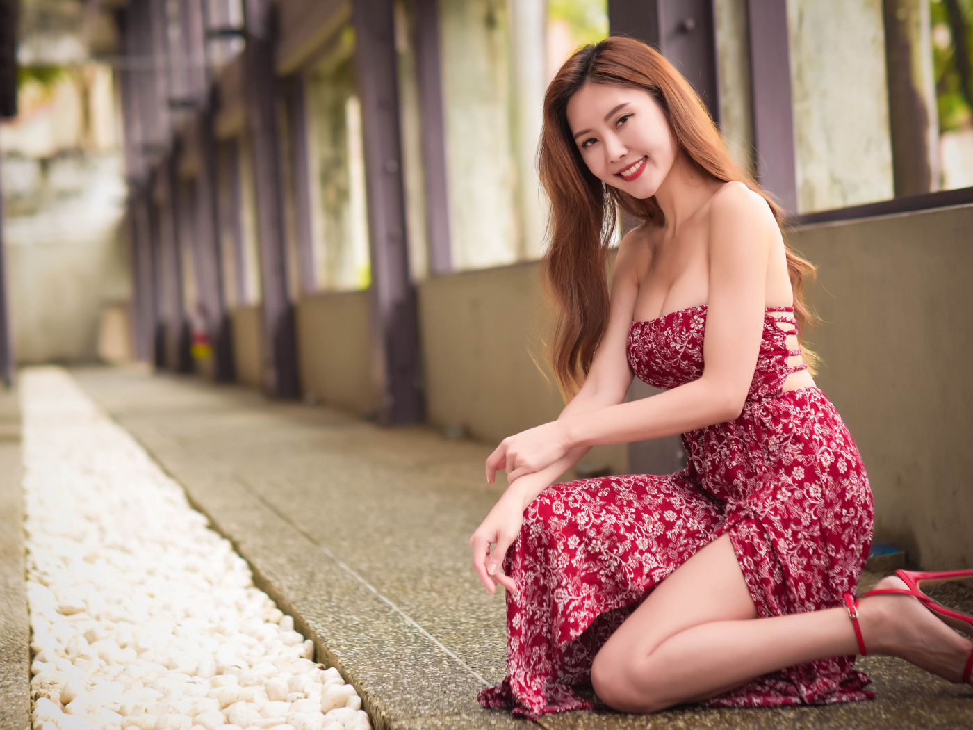 Улыбающаяся азиатка в красном платье у окна 