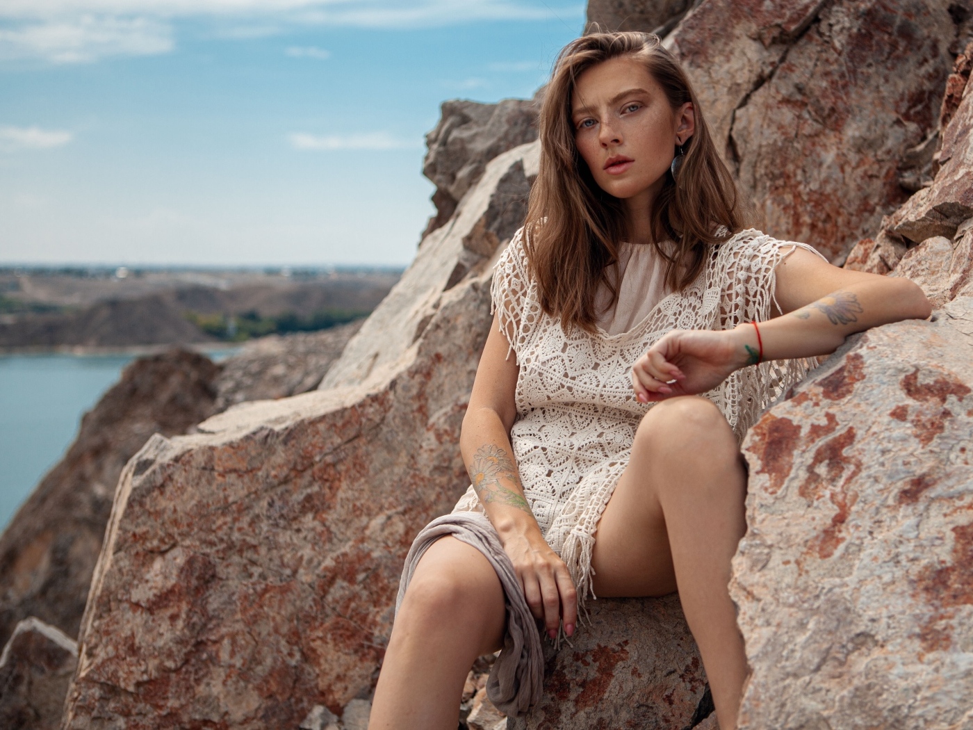 Молодая девушка сидит на камнях