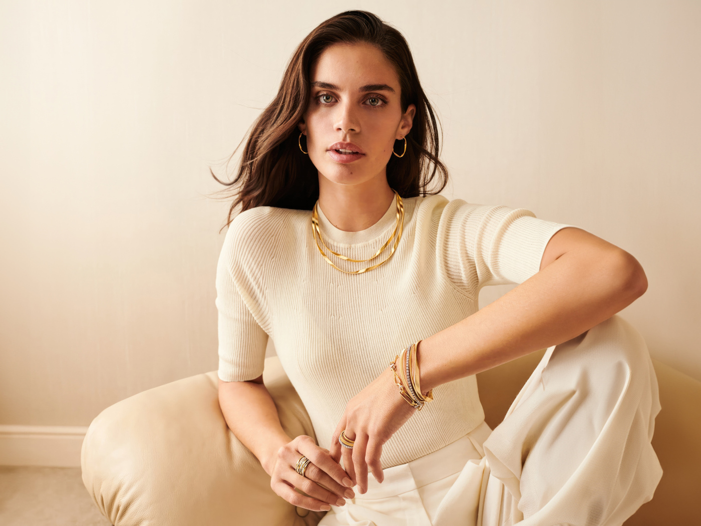 Модель Сара Сампайо в белом наряде сидит в кресле