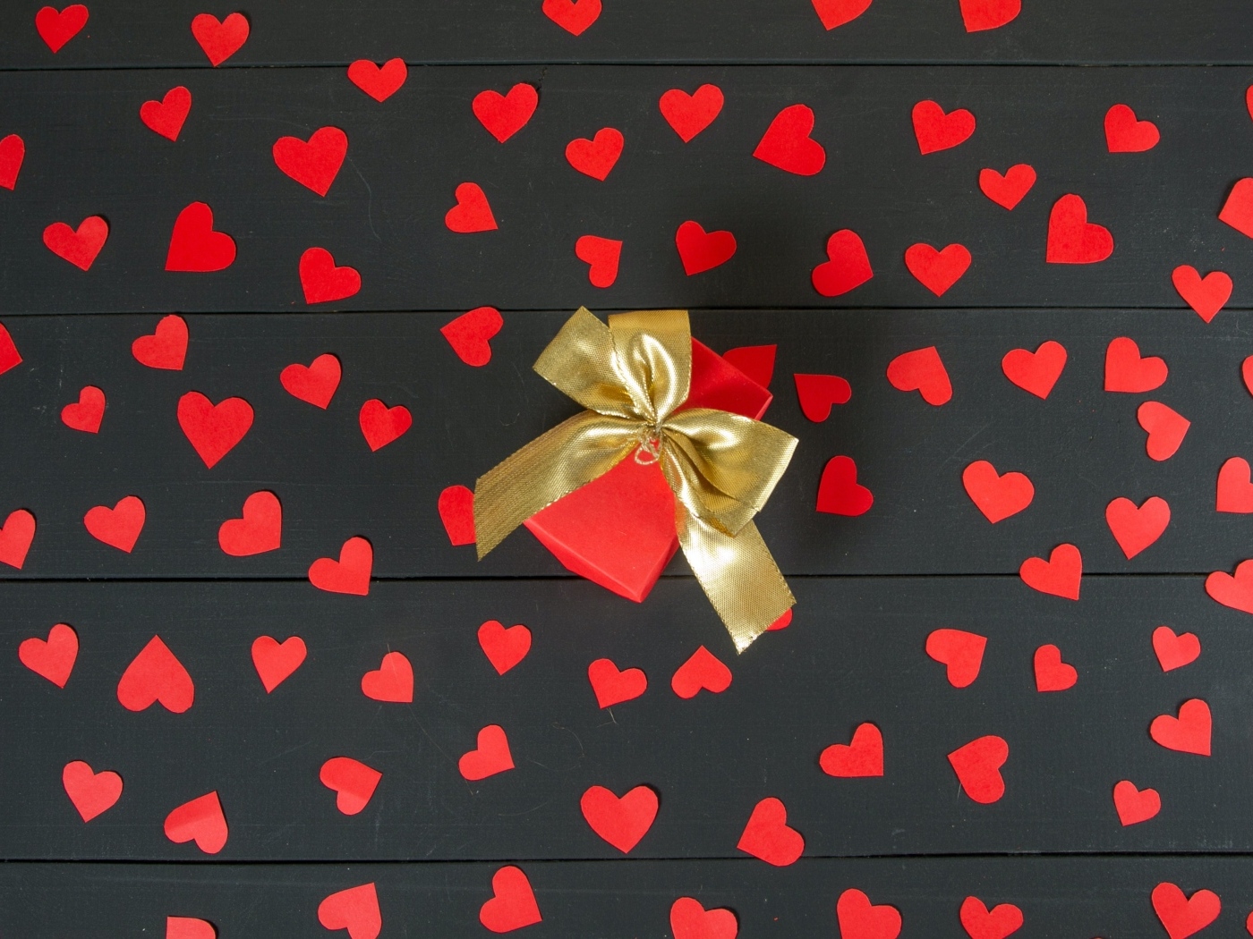 Много маленьких бумажных сердечек с подарком на столе