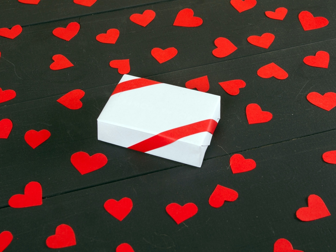 Белая коробка с маленькими бумажными сердечками на столе