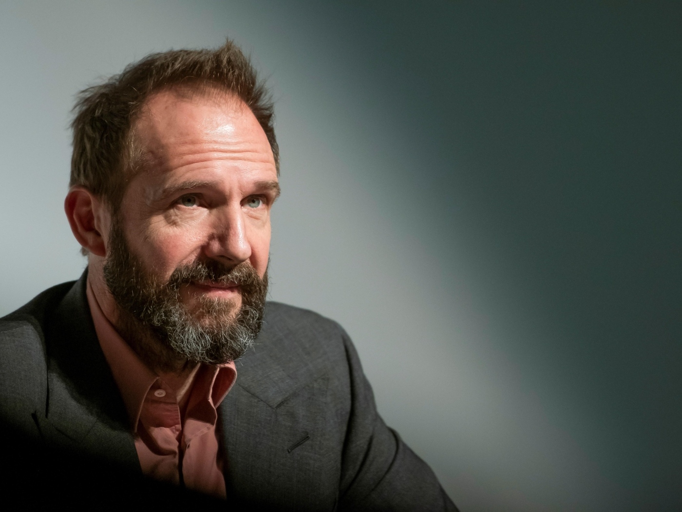 Актер Рэйф Файнс с бородой на сером фоне