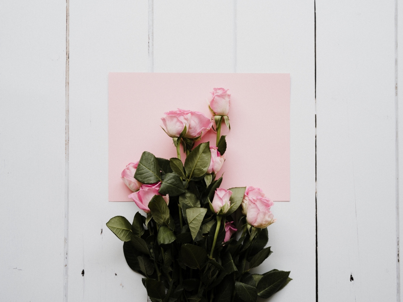 Букет роз с розовым листом бумаги на столе