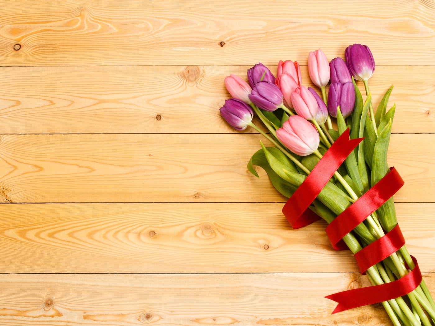 Большой букет тюльпанов с красной лентой на деревянном фоне
