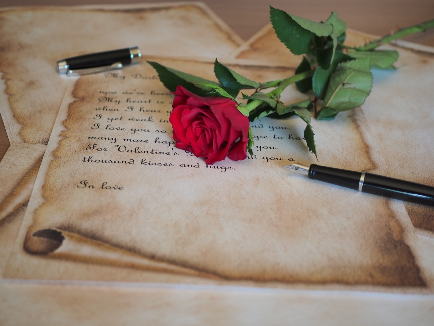 Красная роза с запиской и ручкой на столе