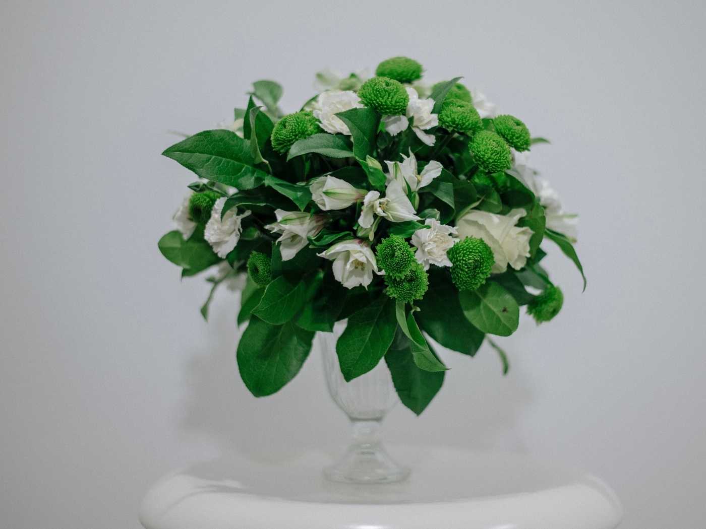 Белый букет с зелеными листьями на сером фоне