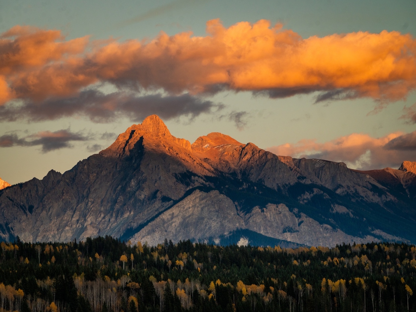 Солнце в облаках освещает вершину горы