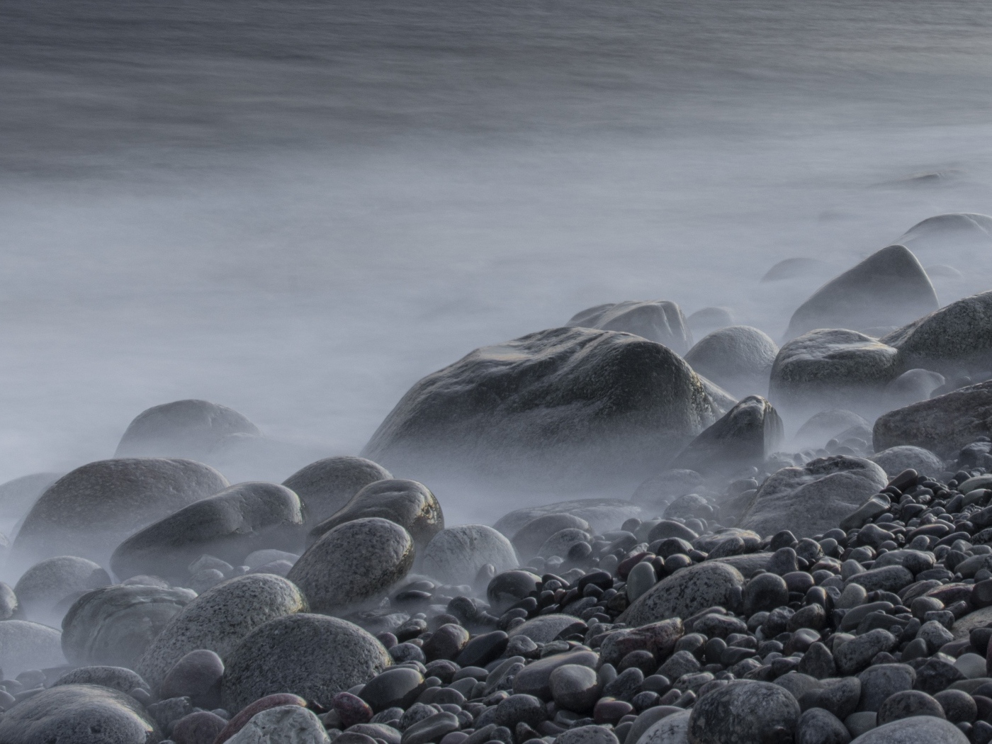 Большие черные камни на берегу моря в тумане