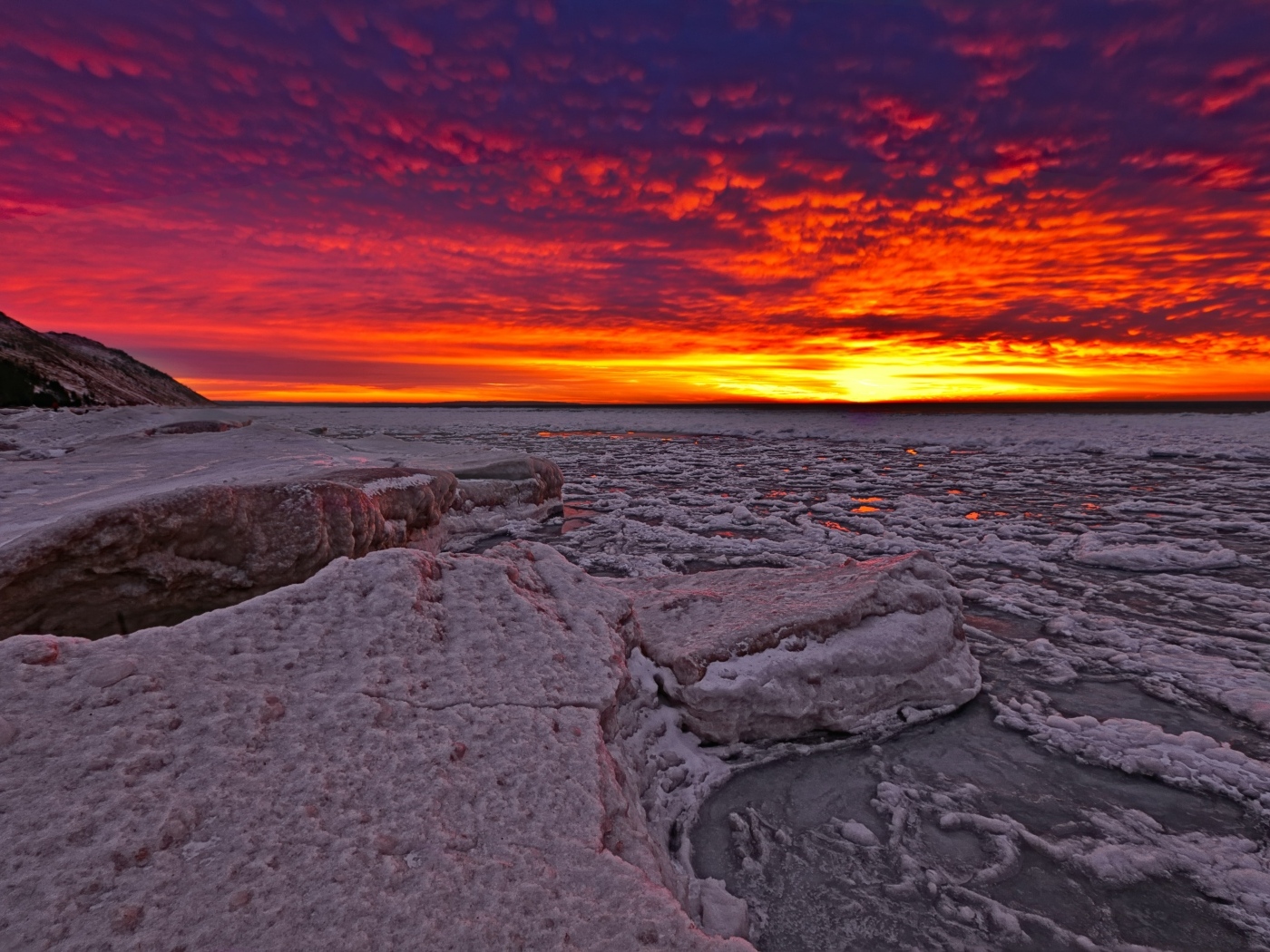 Красный закат солнца покрывает заледеневшее озеро 
