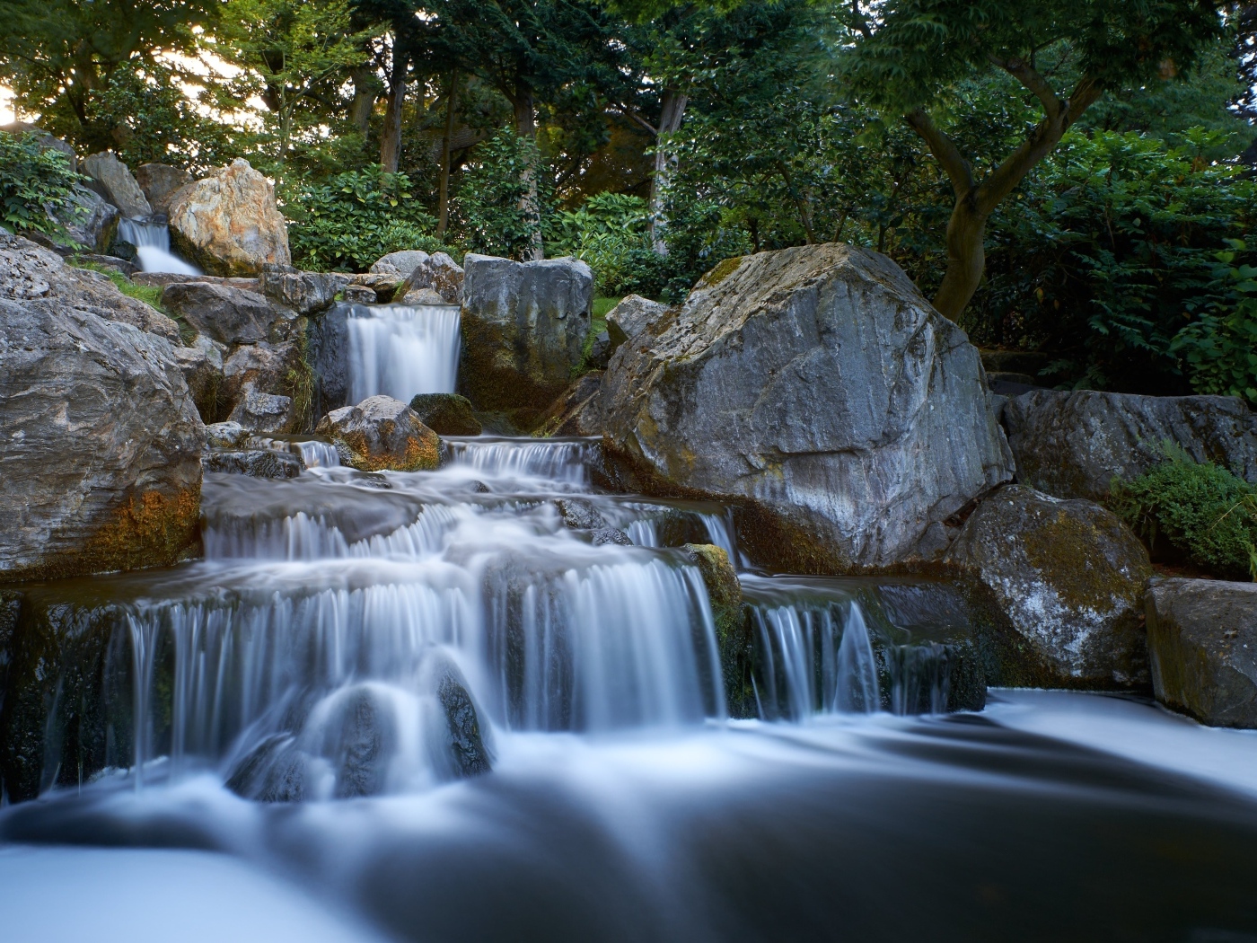 Водопад стекает по большим холодным камням в лесу