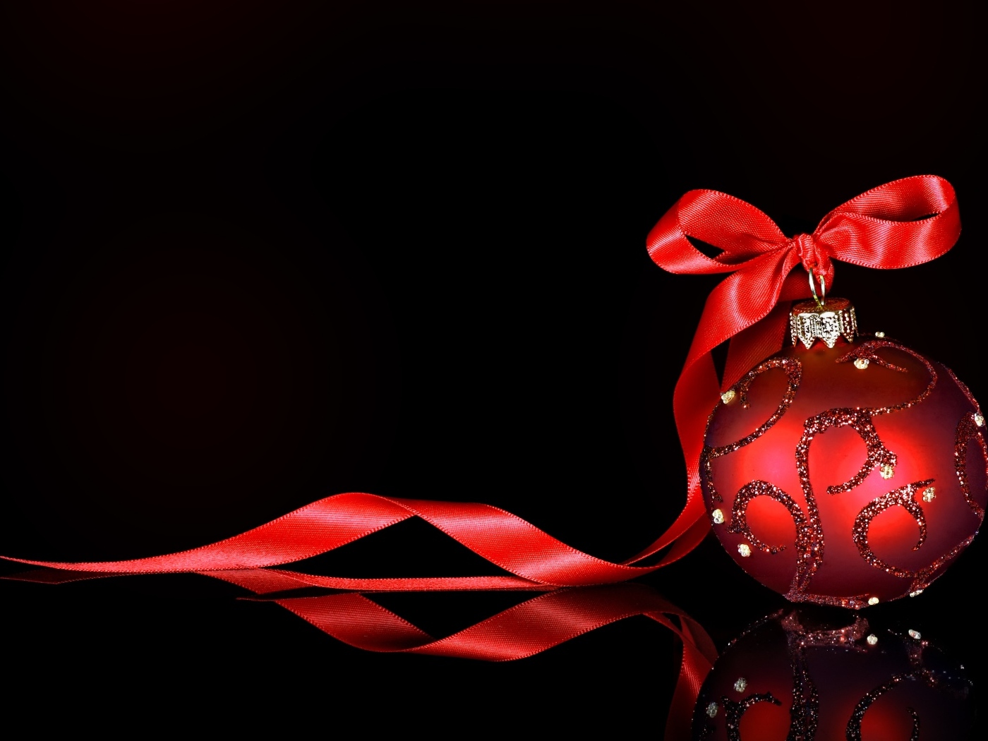 Красный елочный шар с лентой на черном фоне