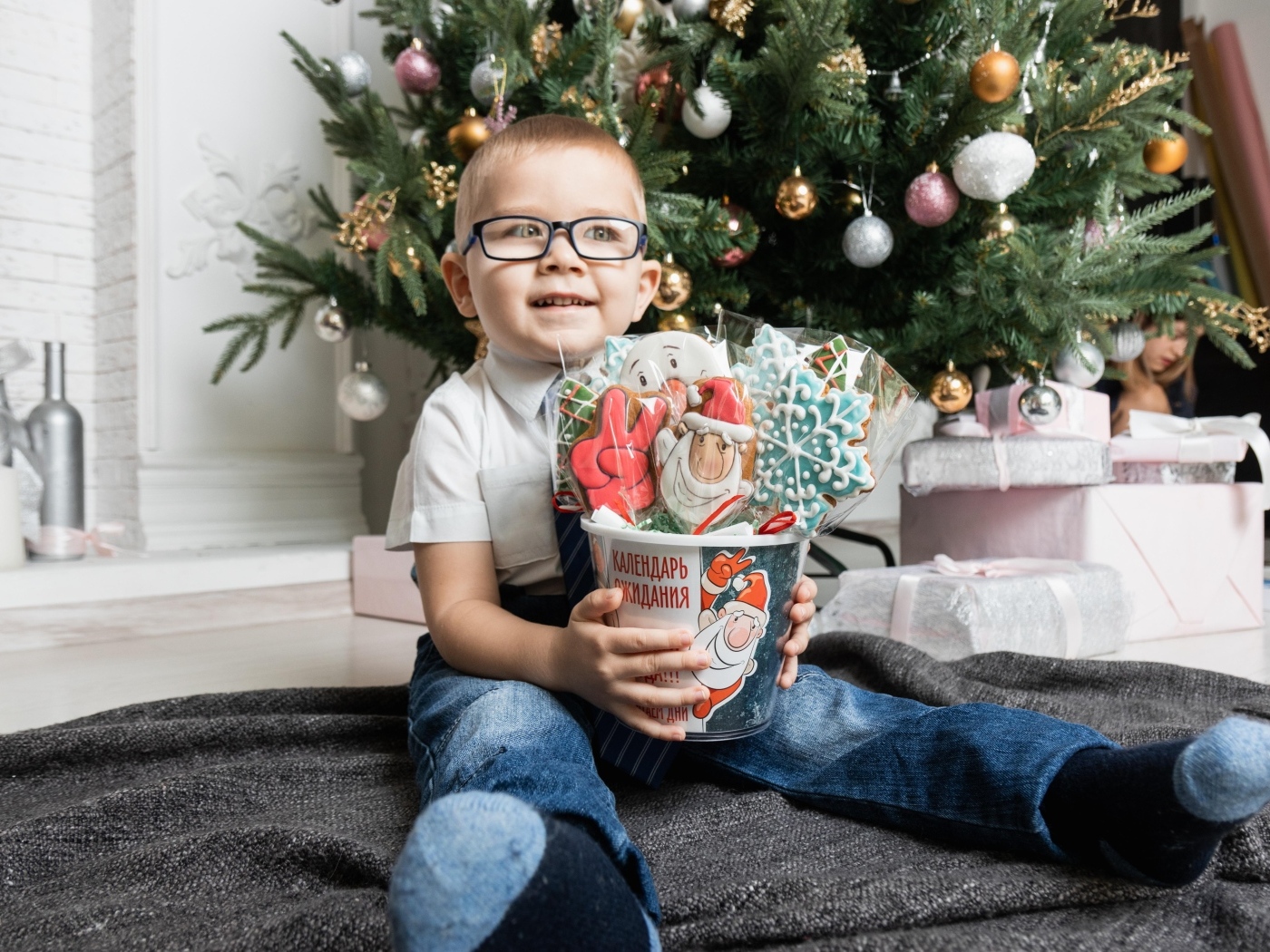 Маленький мальчик с печеньем сидит у ели