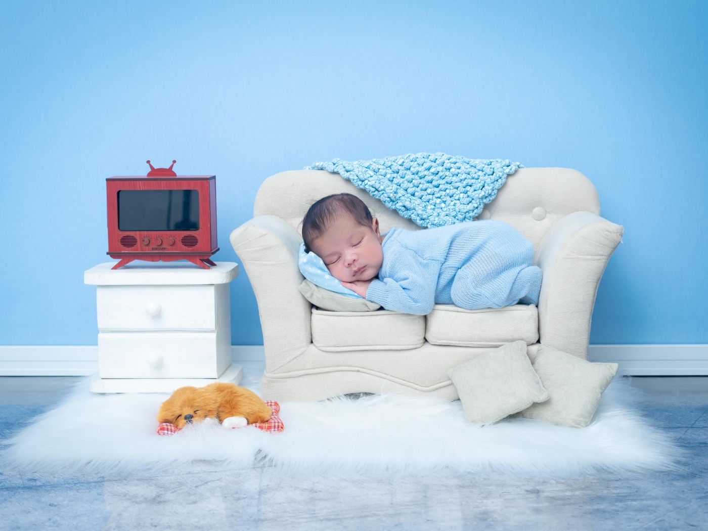 Новорожденный ребенок спит на белом диване на фоне голубой стены